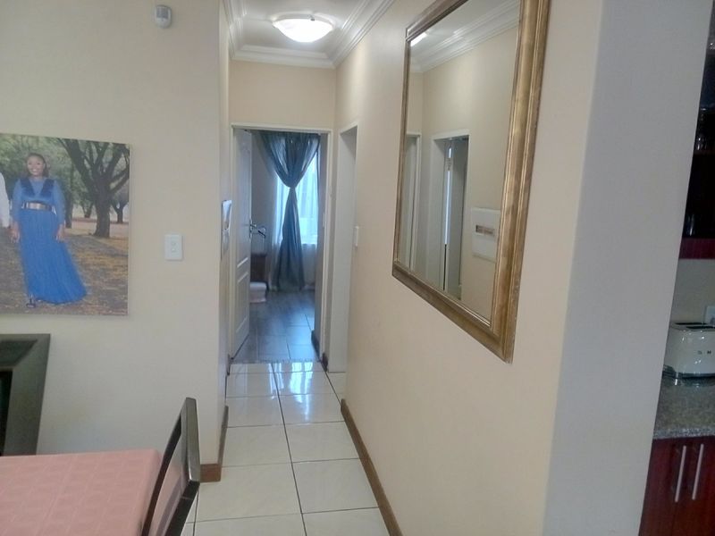 A functional hallway featuring tiled flooring and ceiling cornice, providing access to adjacent rooms within the home.