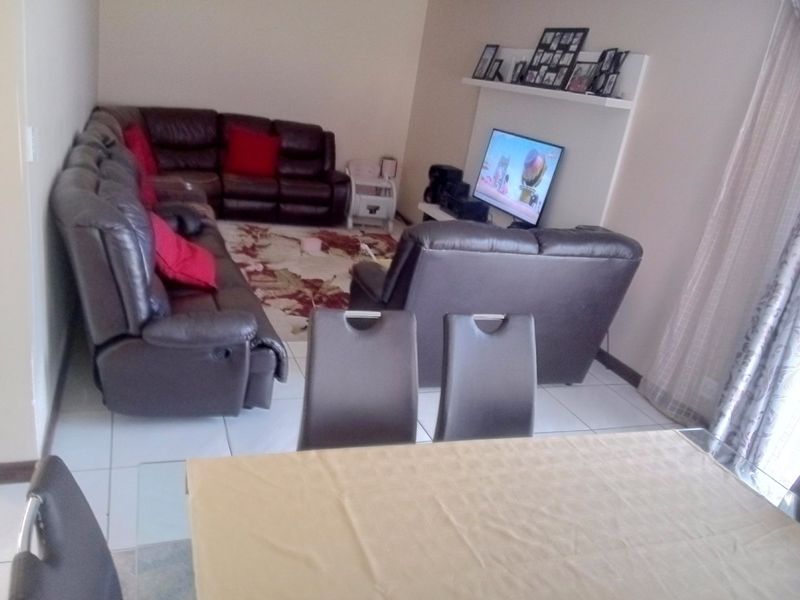 Open plan living and dining area featuring tiled flooring and a built-in wall shelf for media display.
