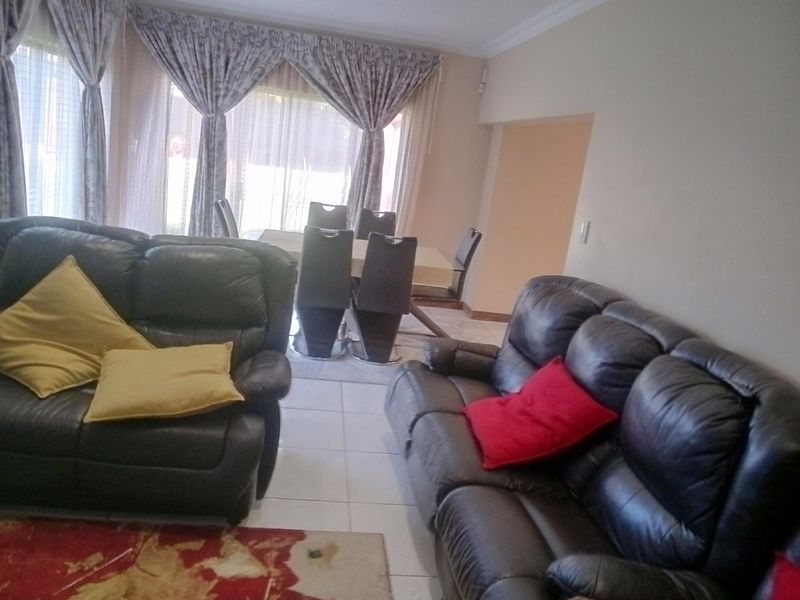 Open-plan living and dining area featuring tiled flooring, decorative cornicing, and large sliding glass doors providing natural light.
