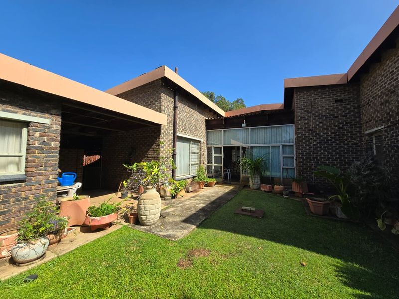 Rear view of the property featuring a brick facade, a covered patio area, and a concrete walkway leading to the main entrance.