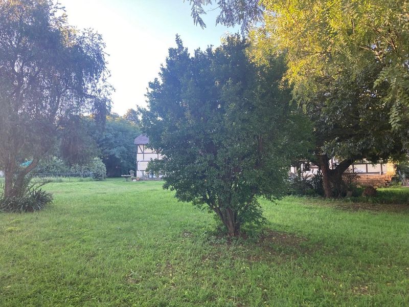 A spacious, well-established garden area featuring mature trees and a large lawn, providing a peaceful outdoor setting.