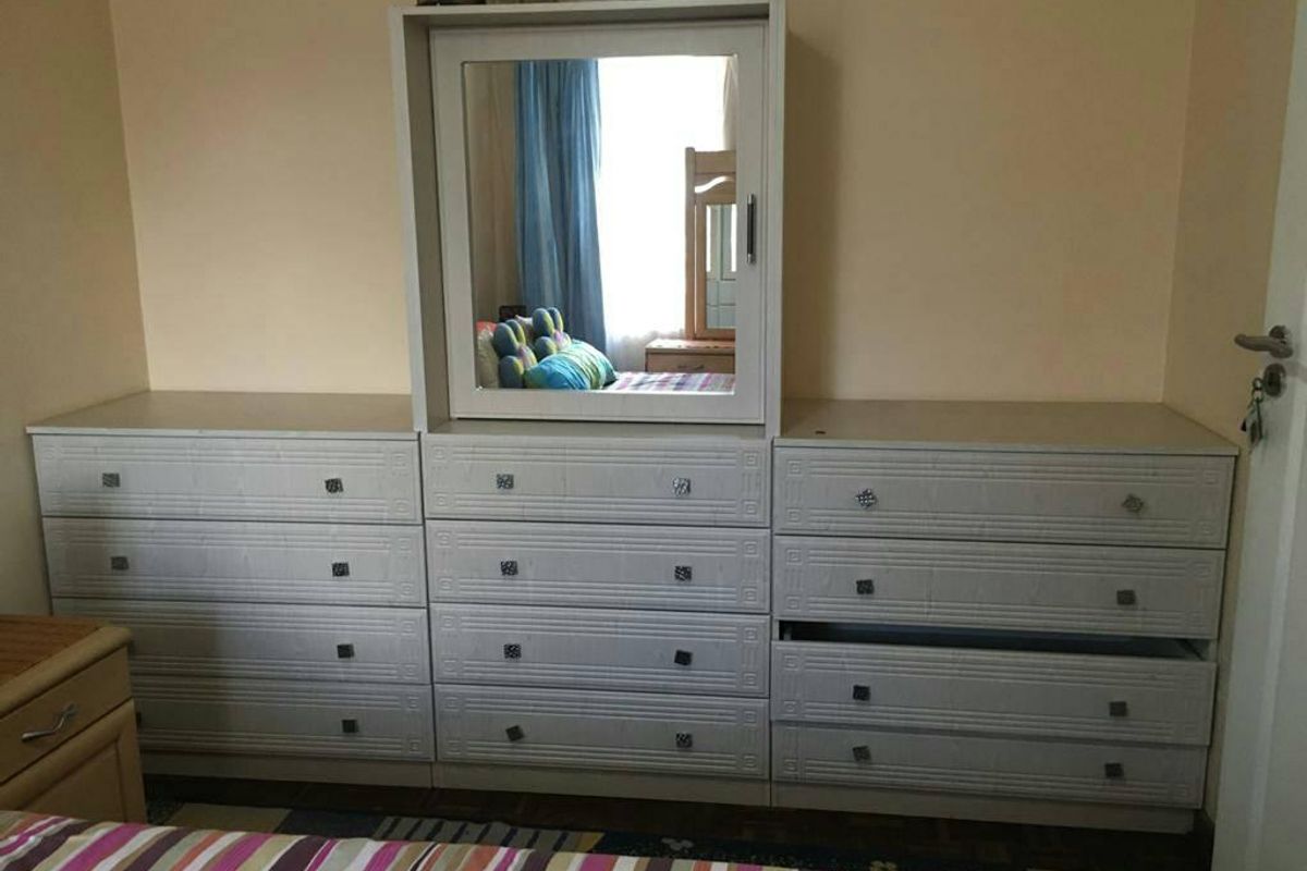 A bedroom interior featuring a large built-in dresser unit with an integrated mirror.