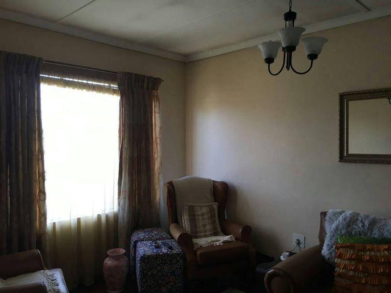 A living room featuring a ceiling light fixture and a window with curtains, providing natural light to the space.
