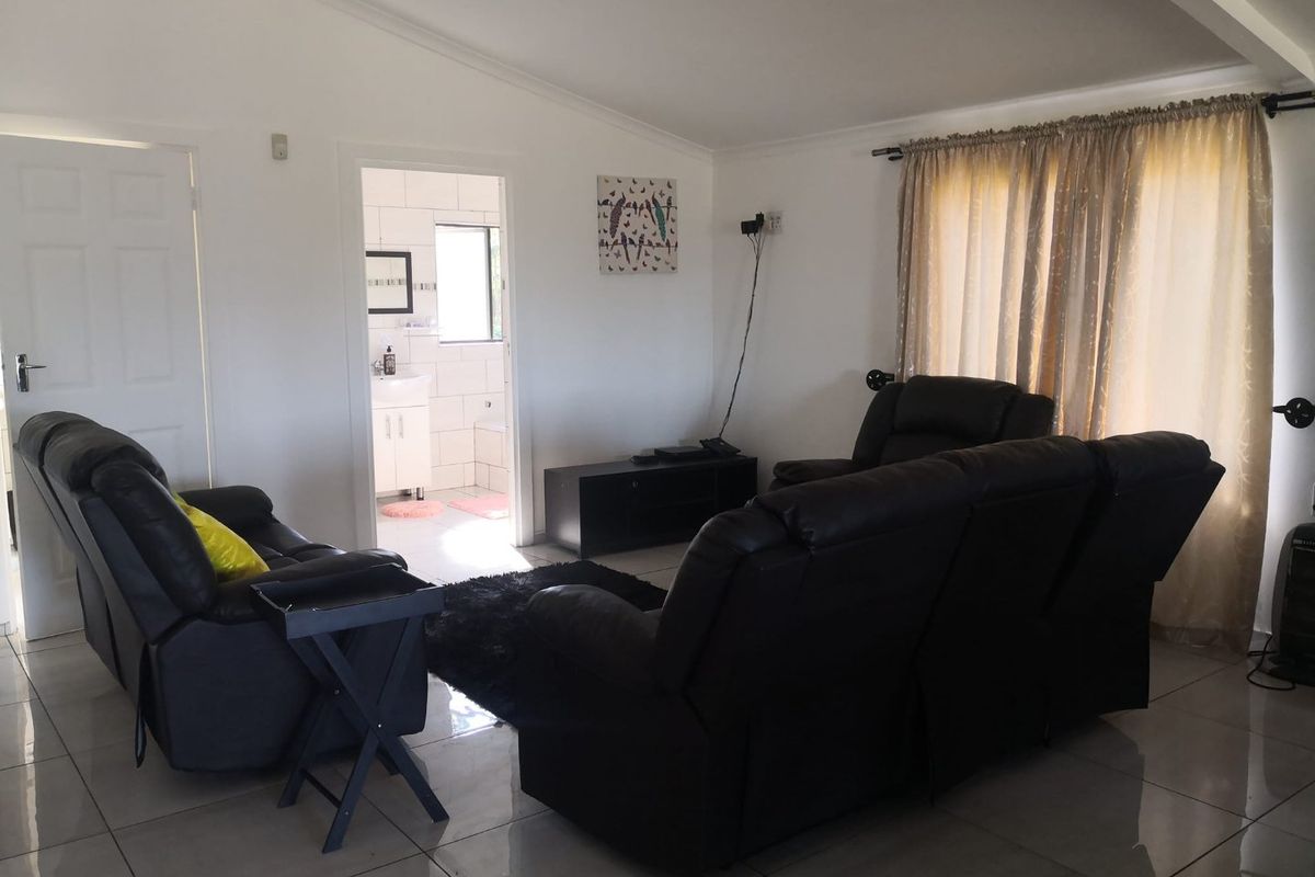 A living room featuring tiled flooring and a vaulted ceiling, with direct access to an adjacent bathroom.