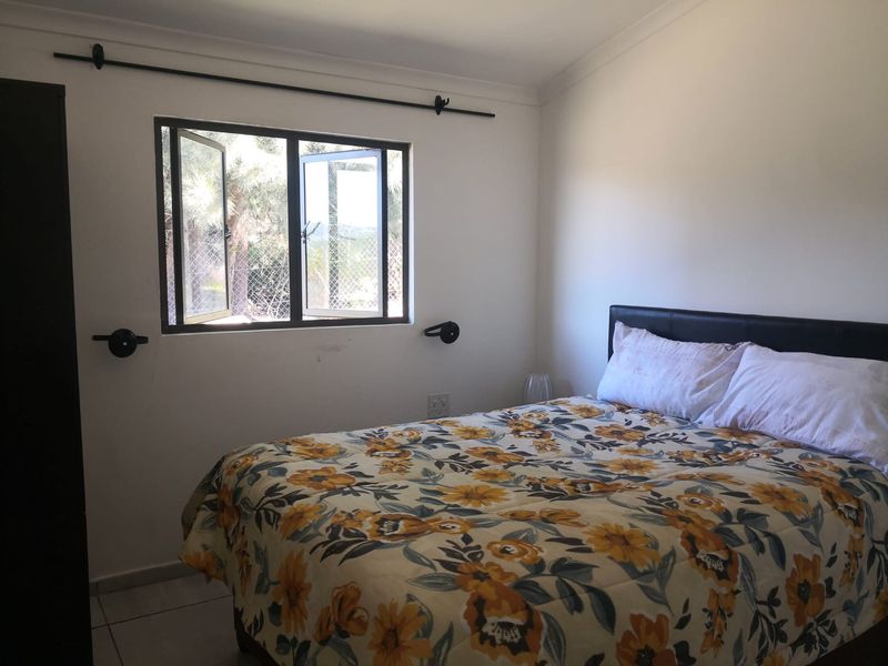 A functional bedroom featuring tiled flooring and a casement window, providing natural light and ventilation.