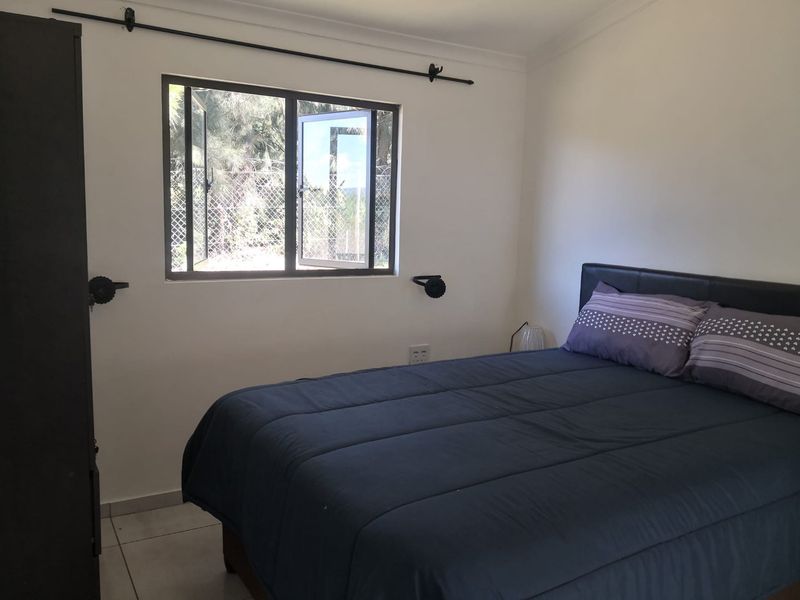 A functional bedroom featuring tiled flooring, a casement window with a curtain rod, and neutral wall finishes.