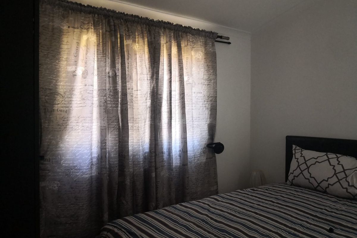 A bedroom featuring a window with installed curtain rod, providing natural light to the space.