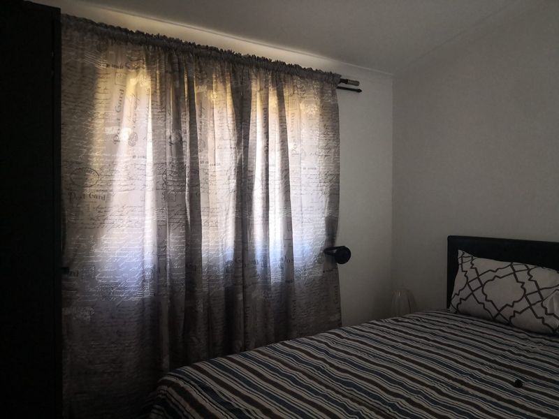 A bedroom featuring a window with installed curtain rod, providing natural light to the space.
