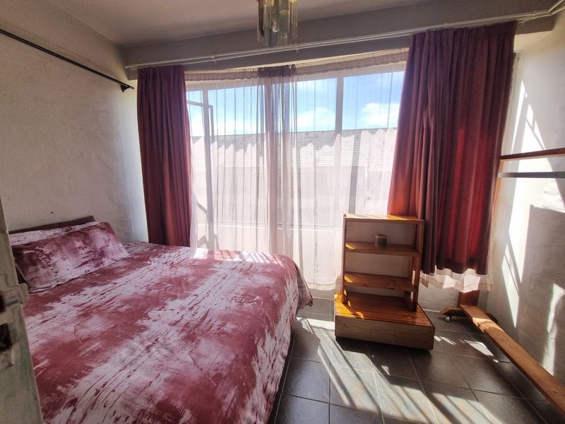 A bedroom featuring tiled flooring and a large window with curtain tracks, providing natural light.