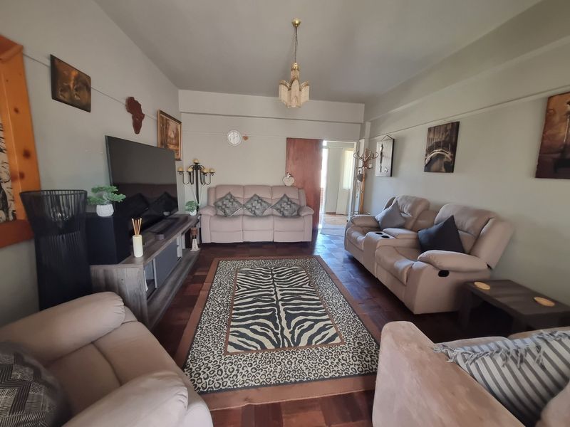 A comfortable living room featuring classic parquet flooring and a central ceiling light fixture, providing a warm and inviting space for relaxation.