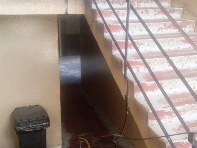 A communal stairwell area showing significant wear and tear with peeling paint on the steps and aged metal handrails.