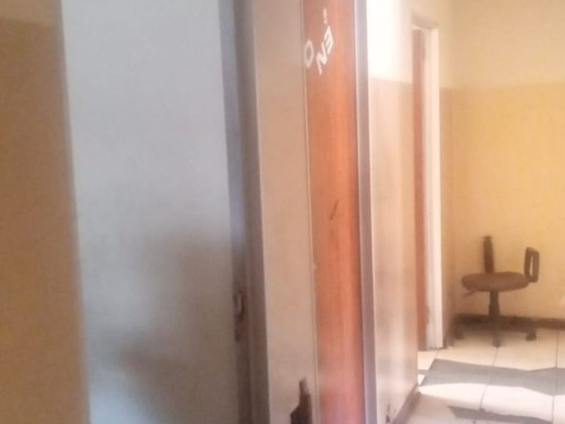 A narrow hallway with tiled flooring and multiple internal doors, showing signs of wear and requiring maintenance to the wall finishes and door frames.