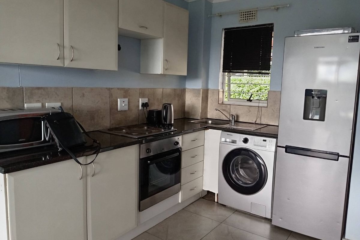 Functional kitchen featuring granite countertops, built-in oven and hob, tiled backsplash, and dedicated space for laundry appliances.