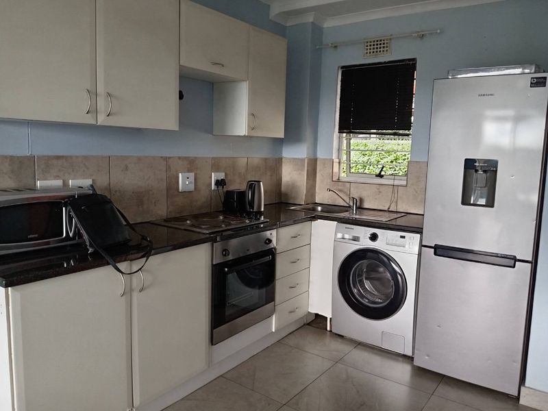 Functional kitchen featuring granite countertops, built-in oven and hob, tiled backsplash, and dedicated space for laundry appliances.