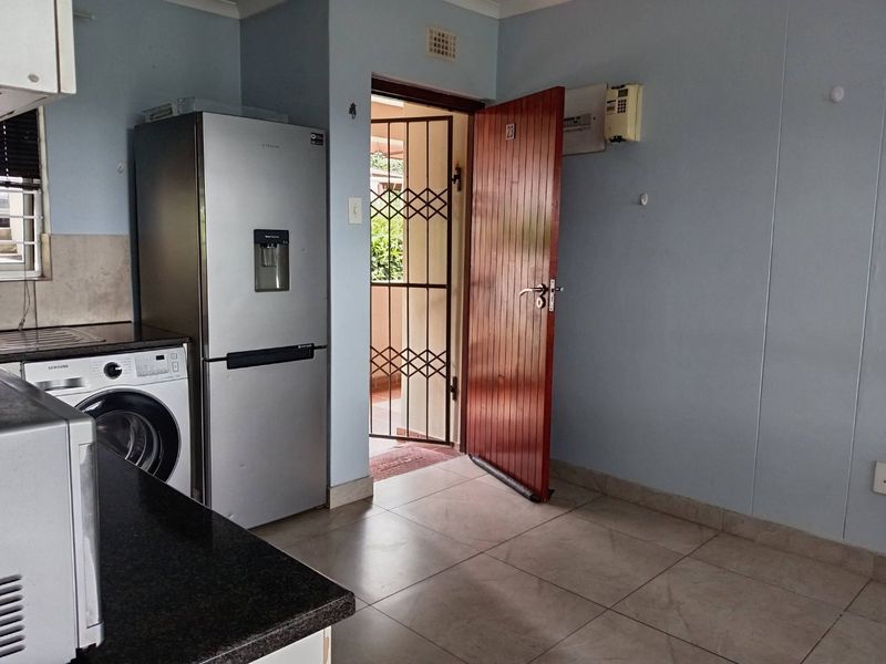 Kitchen area featuring tiled flooring, granite countertops, and direct access to an exterior entrance with a security gate.