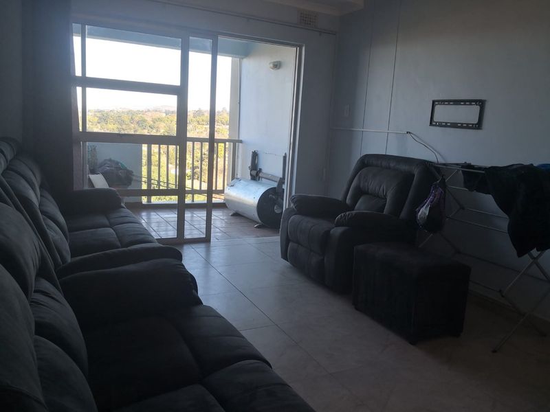 Living room area featuring tiled flooring and a sliding glass door providing access to an outdoor balcony with scenic views.