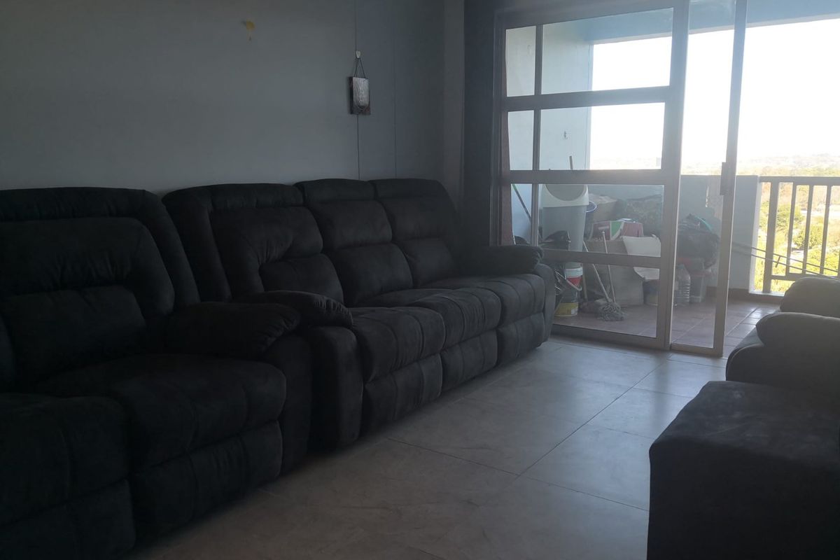 Living room area featuring tiled flooring and a large sliding glass door providing access to an outdoor balcony space.