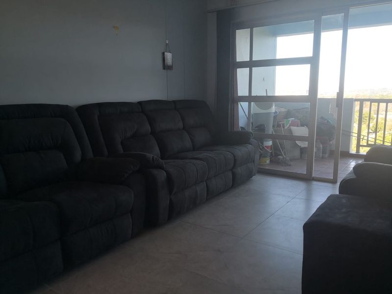 Living room area featuring tiled flooring and a large sliding glass door providing access to an outdoor balcony space.