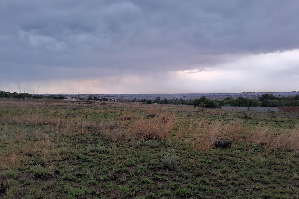 A wide-angle view of the vacant residential land under a cloudy sky, showcasing the open landscape and surrounding area.
