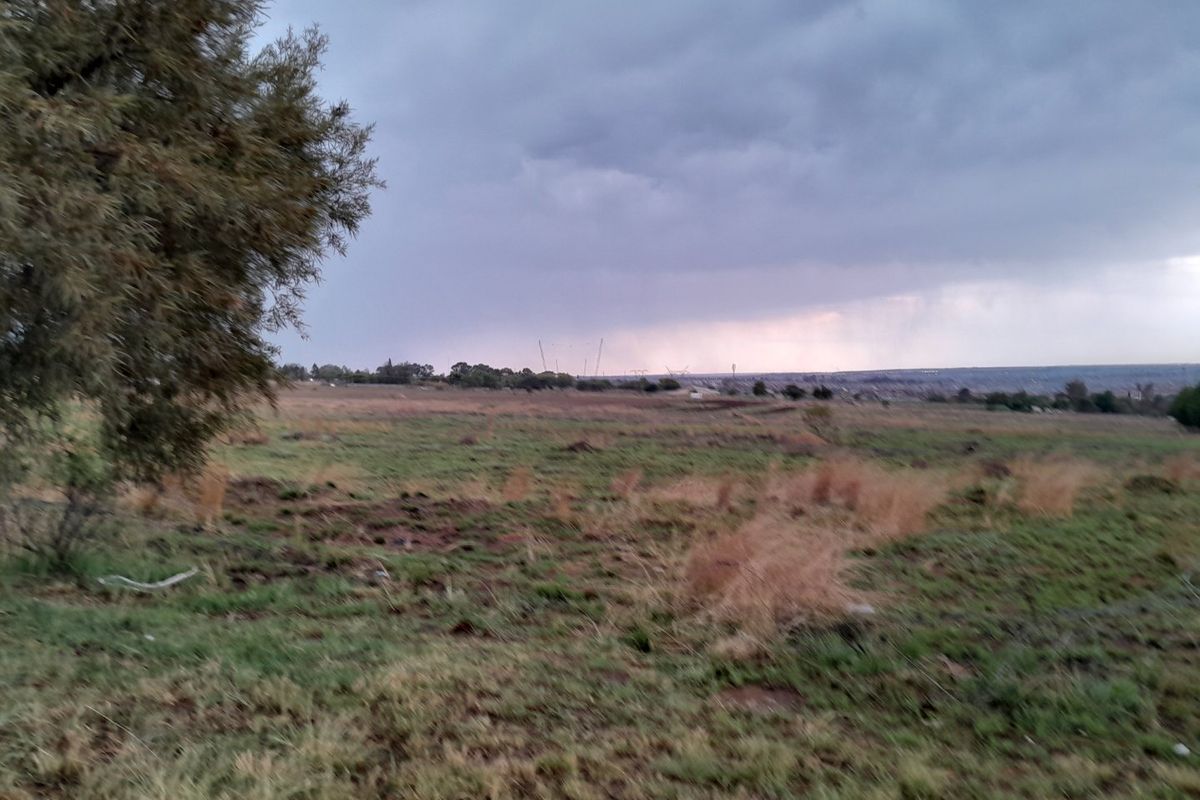 An expansive view of the vacant residential land under a cloudy sky, showcasing the natural terrain and open landscape.