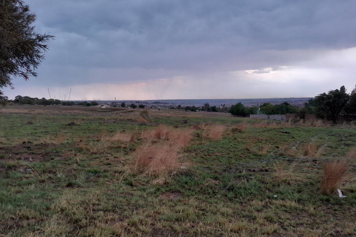 A wide-angle view of the vacant residential land, showcasing the expansive landscape and natural terrain under a cloudy sky.