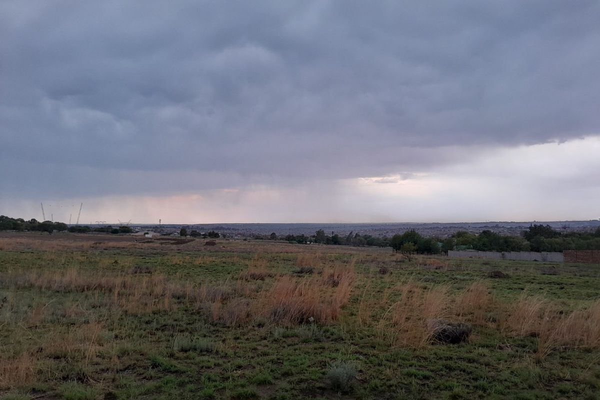 A wide-angle view of an expansive, undeveloped residential plot featuring natural grassland under a cloudy sky.