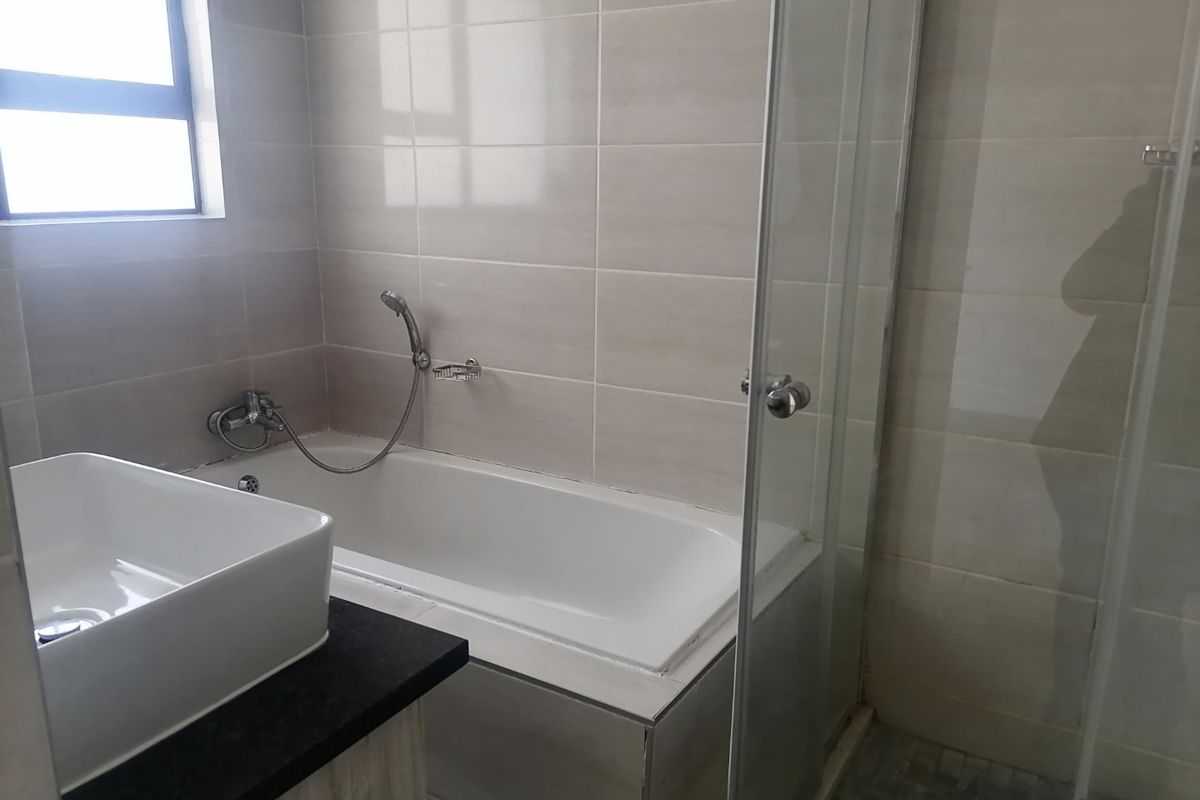 A modern bathroom featuring a built-in bathtub, a separate glass-enclosed shower, and a contemporary vessel sink set on a vanity countertop.