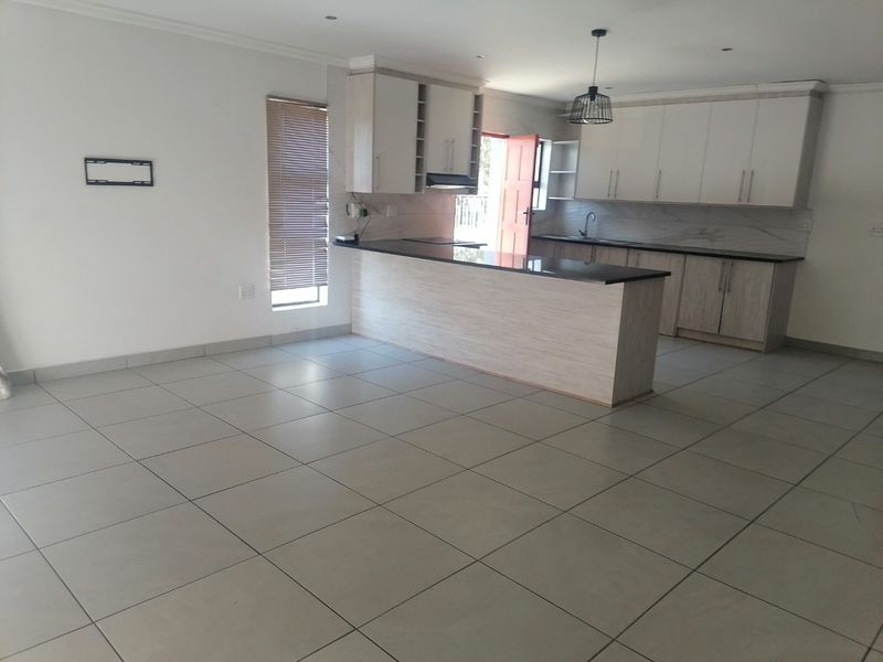 Spacious open-plan kitchen and living area featuring modern built-in cabinetry, granite countertops, and neutral tiled flooring throughout.