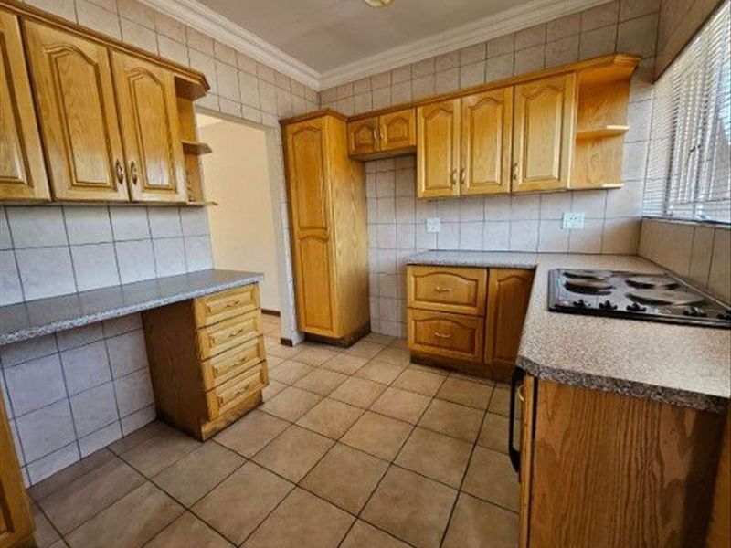 A functional kitchen featuring traditional wooden cabinetry, laminate countertops, tiled backsplash, and a built-in hob, offering a classic layout ready for modernization.