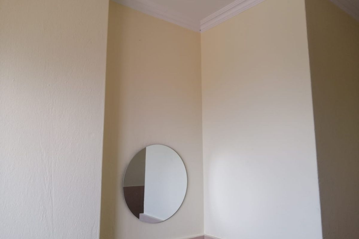 A simple bathroom corner featuring neutral walls, crown molding, and a tiled splashback.
