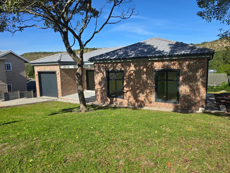 A modern single-story face brick house featuring a tiled roof, dark aluminium window frames, and an integrated single garage.