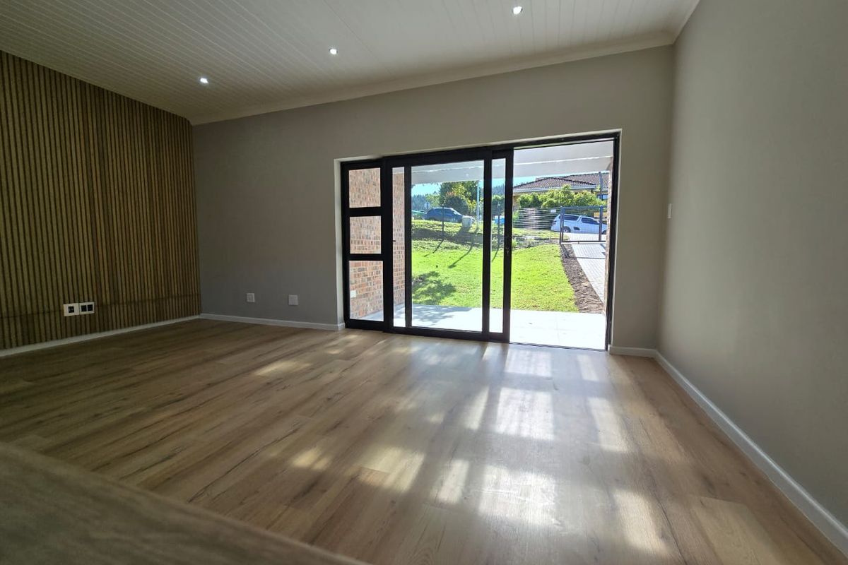 Spacious living area featuring modern laminate flooring, a stylish timber slat feature wall, recessed lighting, and direct access to the garden through sliding doors.