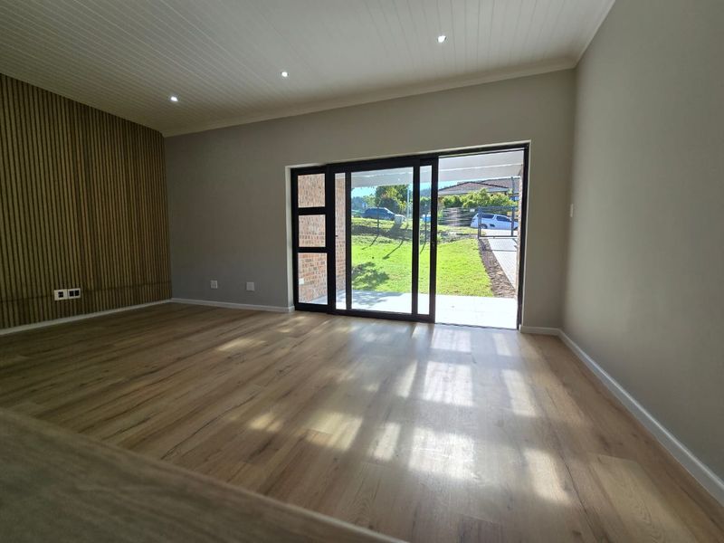 Spacious living area featuring modern laminate flooring, a stylish timber slat feature wall, recessed lighting, and direct access to the garden through sliding doors.