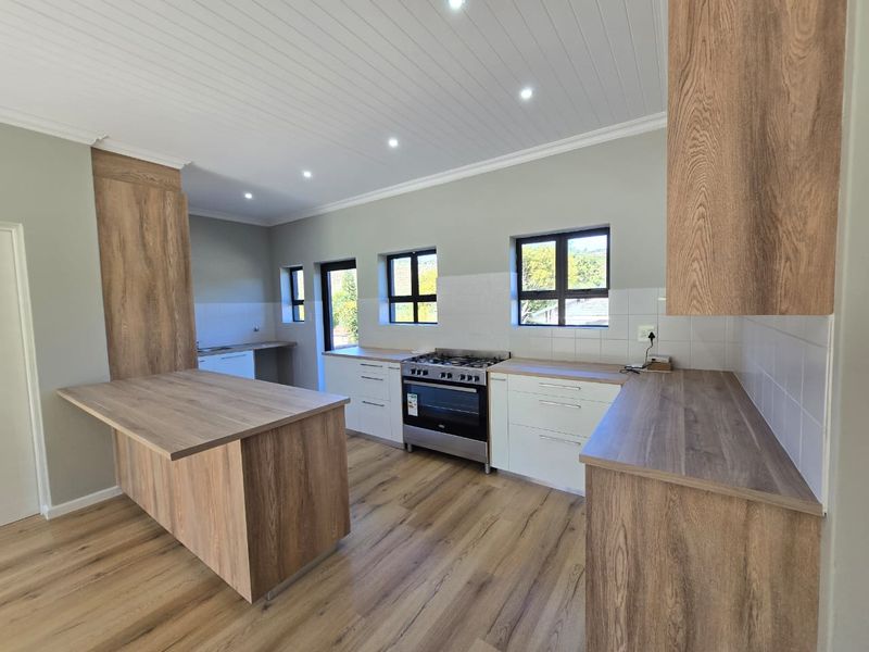 Modern kitchen featuring wood-look cabinetry, laminate countertops, gas stove, and recessed lighting in a clean, open-plan layout.