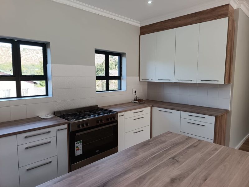 Modern kitchen featuring white cabinetry, wood-look laminate countertops, a built-in gas stove and oven, and a clean tiled backsplash.