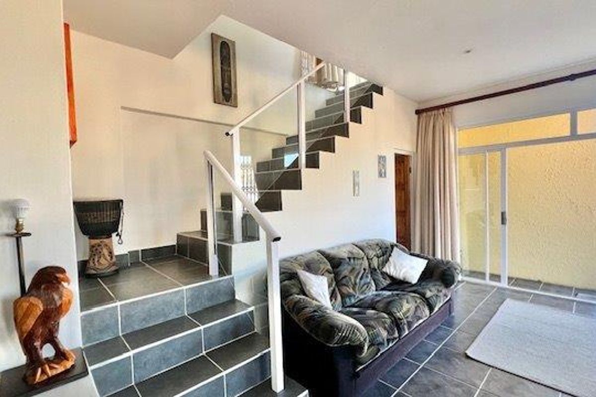 Living area featuring a tiled staircase with a modern glass balustrade and large sliding doors providing access to the outdoor patio.