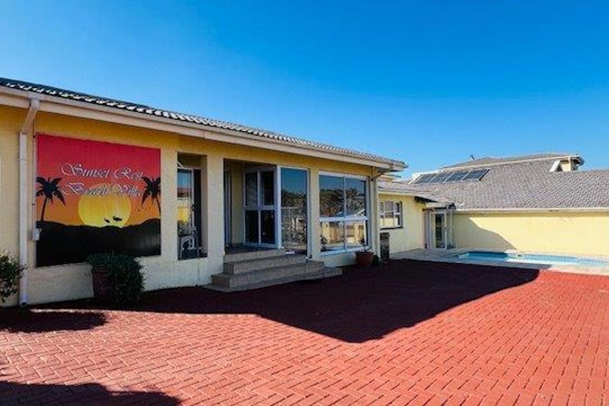 Rear exterior view of the property featuring a paved patio area, swimming pool, and solar panels on the roof.