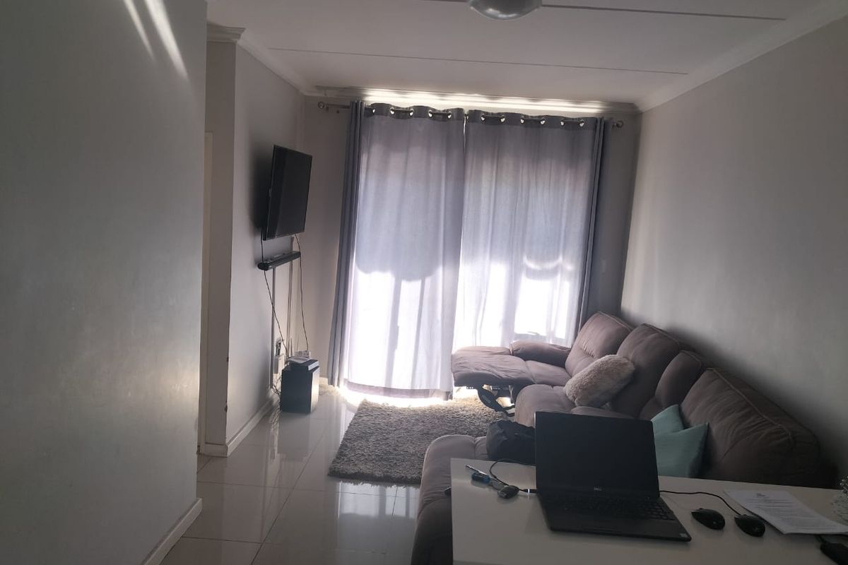 A living room featuring tiled flooring and a sliding glass door that provides natural light.