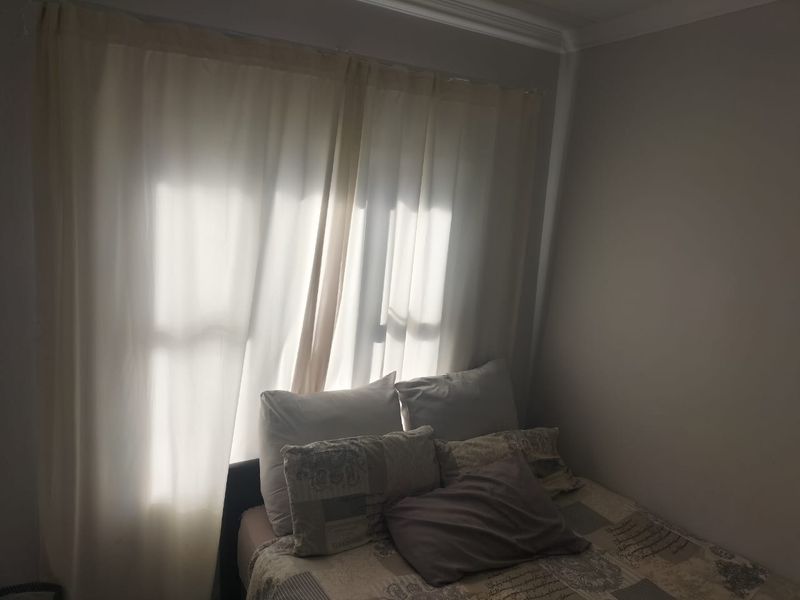 A bedroom featuring a window with curtains and decorative cornice detailing.