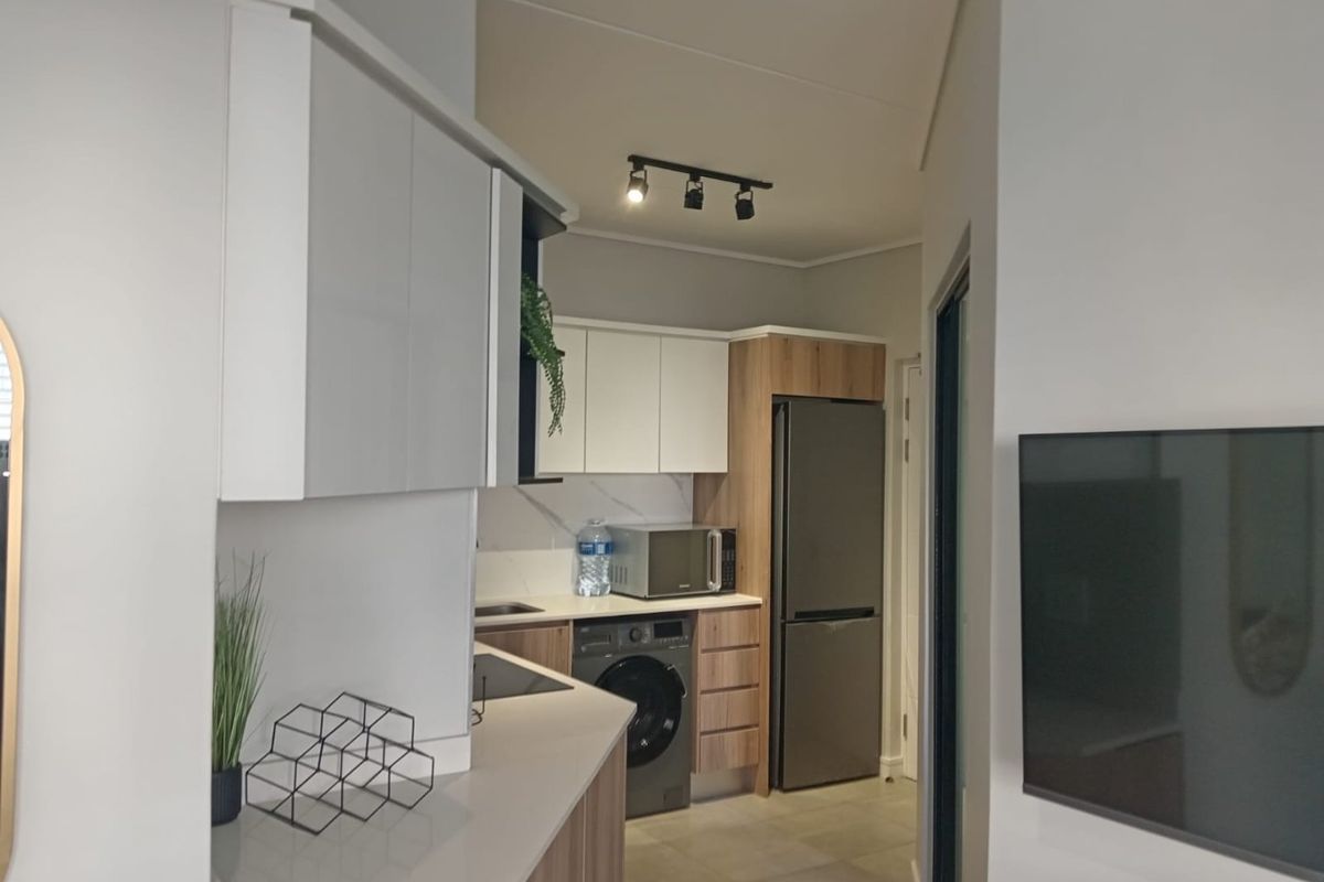 Modern kitchen featuring sleek two-tone cabinetry, stone countertops, and integrated appliances, offering a clean and functional workspace within an open-plan layout.