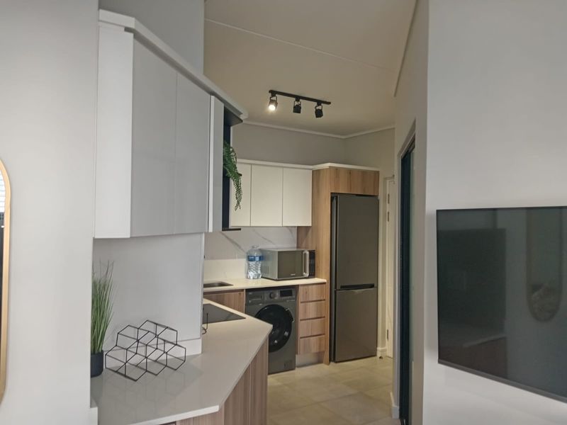 Modern kitchen featuring sleek two-tone cabinetry, stone countertops, and integrated appliances, offering a clean and functional workspace within an open-plan layout.