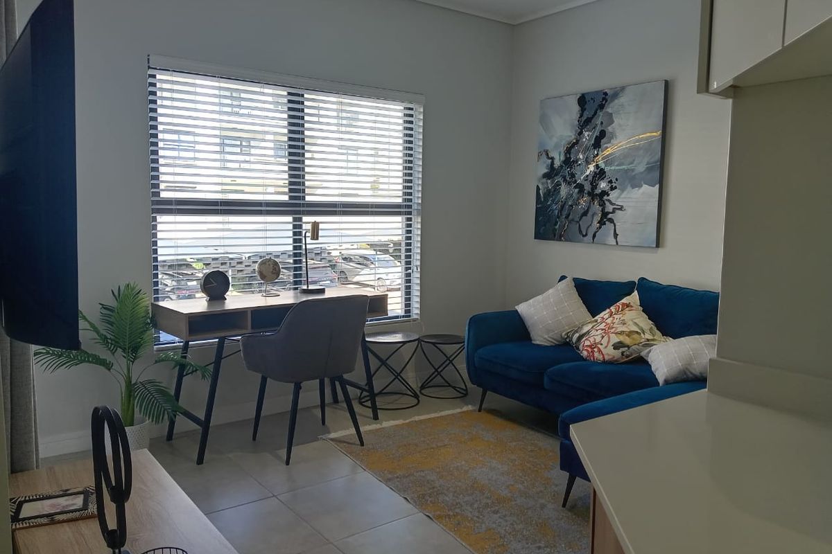 A well-lit living room featuring neutral tiled flooring and modern venetian blinds, offering a comfortable and functional space.