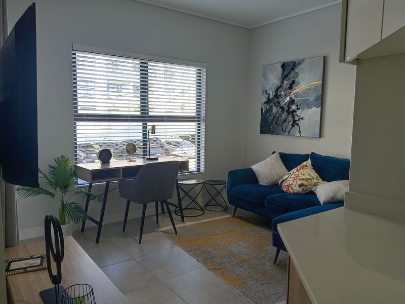 A well-lit living room featuring neutral tiled flooring and modern venetian blinds, offering a comfortable and functional space.