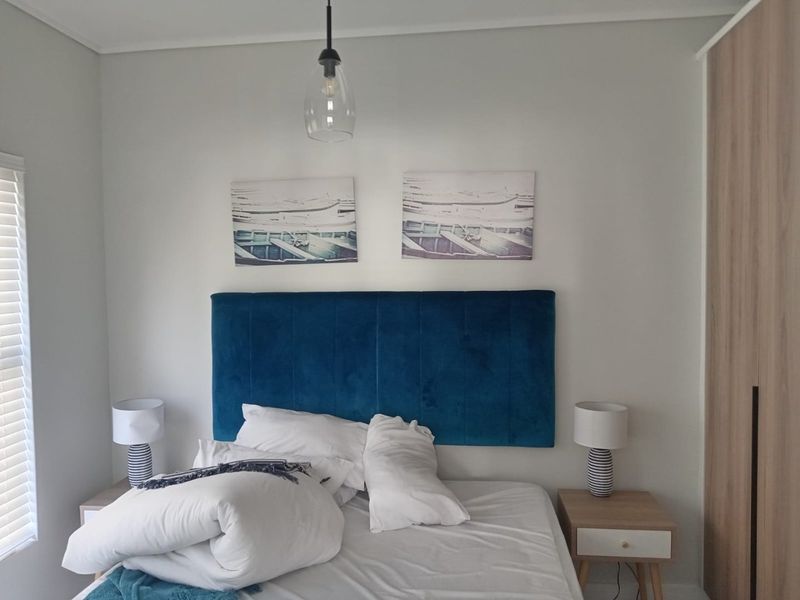 A well-maintained bedroom featuring a built-in wardrobe, modern pendant lighting, and venetian blinds, offering a clean and functional living space.