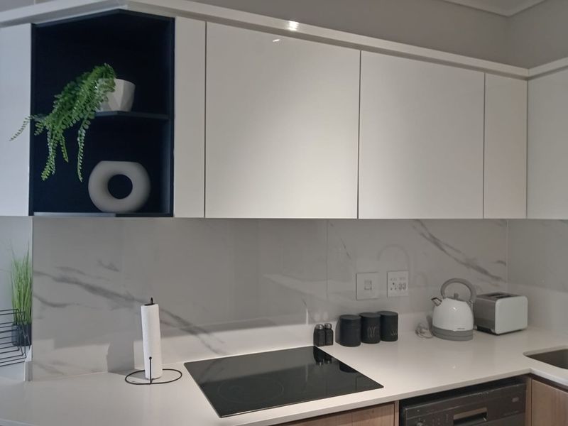 Modern kitchen featuring sleek white cabinetry, a marble-look splashback, quartz countertops, and a built-in induction hob.