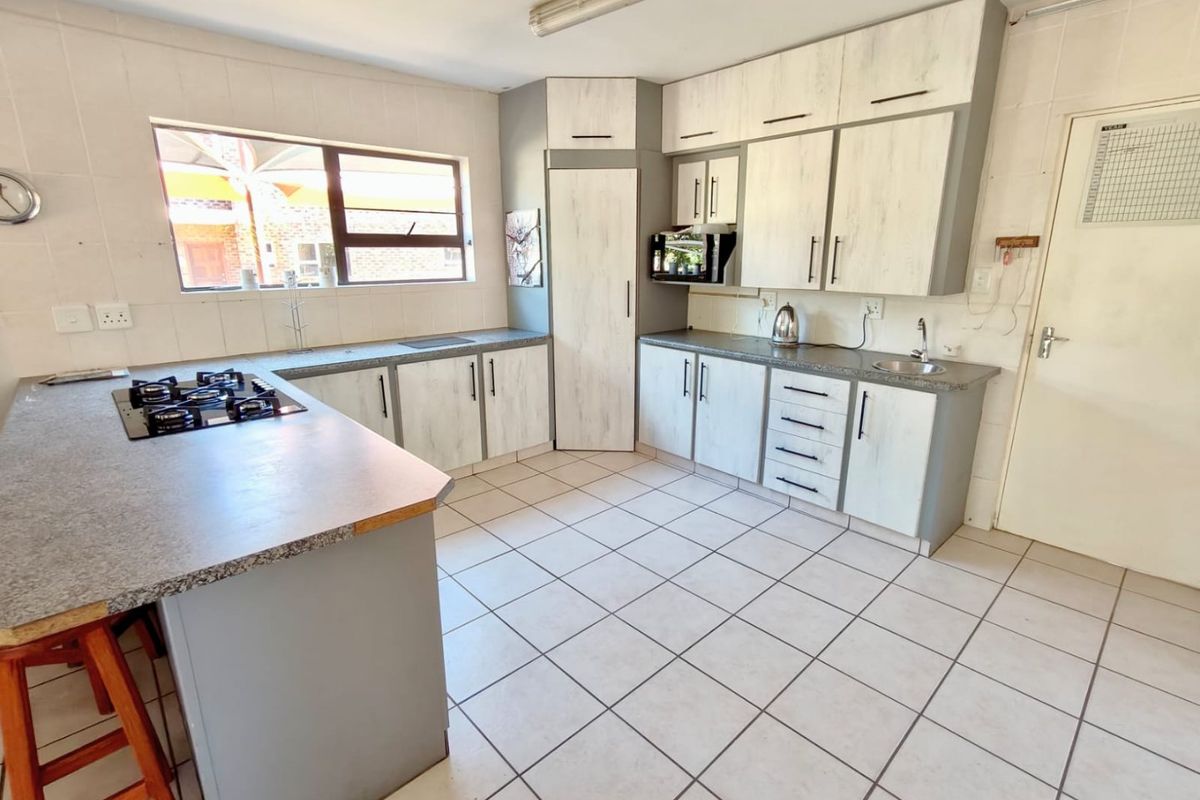 Functional kitchen featuring built-in cabinetry, gas hob, tiled flooring, and ample counter space, offering a practical layout for daily meal preparation.