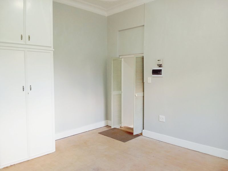 An empty bedroom featuring built-in cupboards, louvered closet doors, and neutral wall finishes, providing a blank canvas for interior design.