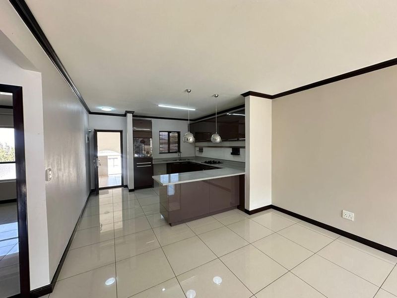 Modern open-plan kitchen featuring high-gloss cabinetry, stone countertops, and sleek tiled flooring, seamlessly integrated into the living space.