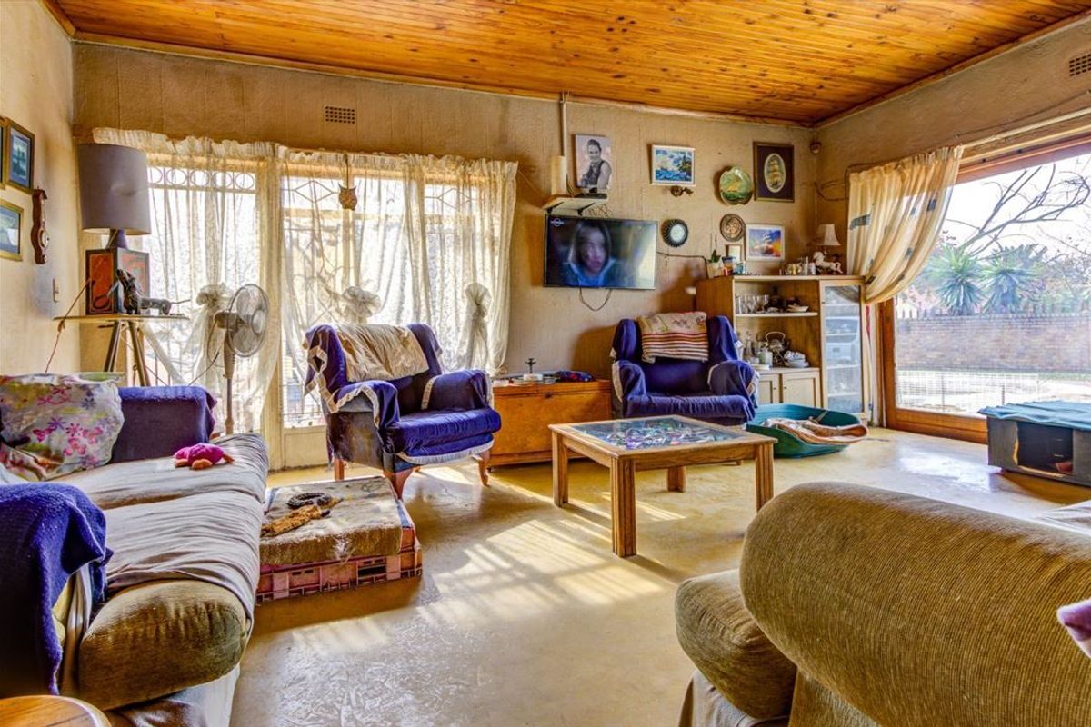 A living room featuring a timber ceiling and sliding glass doors with security gates, offering access to the outdoor area.