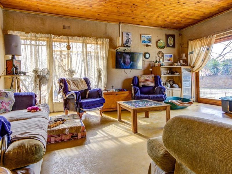 A living room featuring a timber ceiling and sliding glass doors with security gates, offering access to the outdoor area.